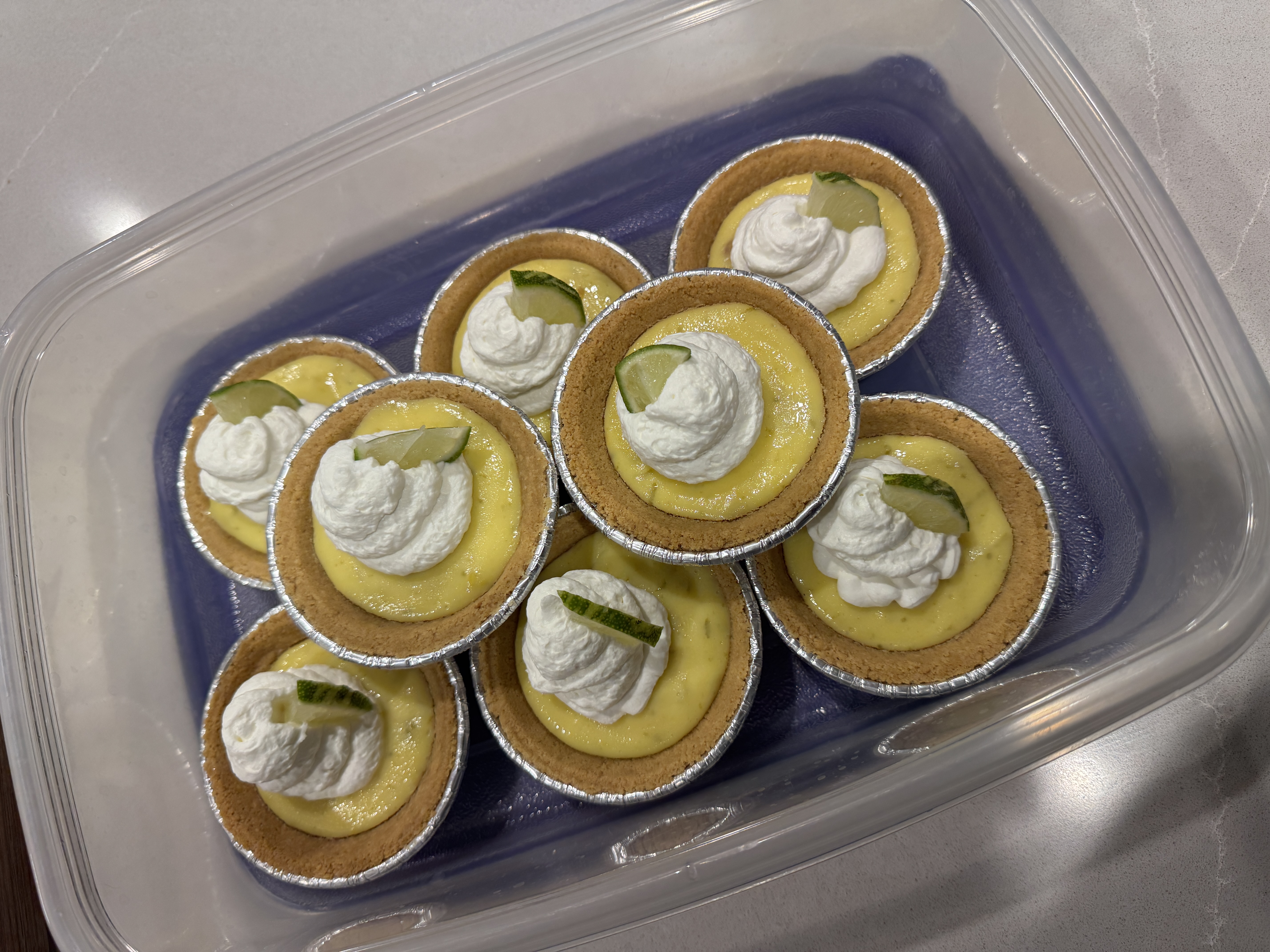 Mini key lime pies topped with whipped cream and a thin slice of lime.