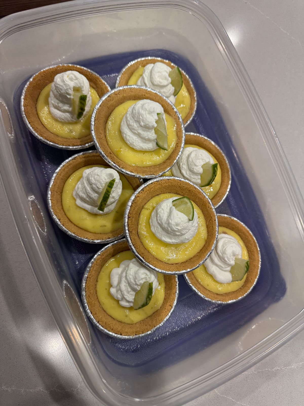 Mini key lime pies topped with whipped cream and a thin slice of lime.